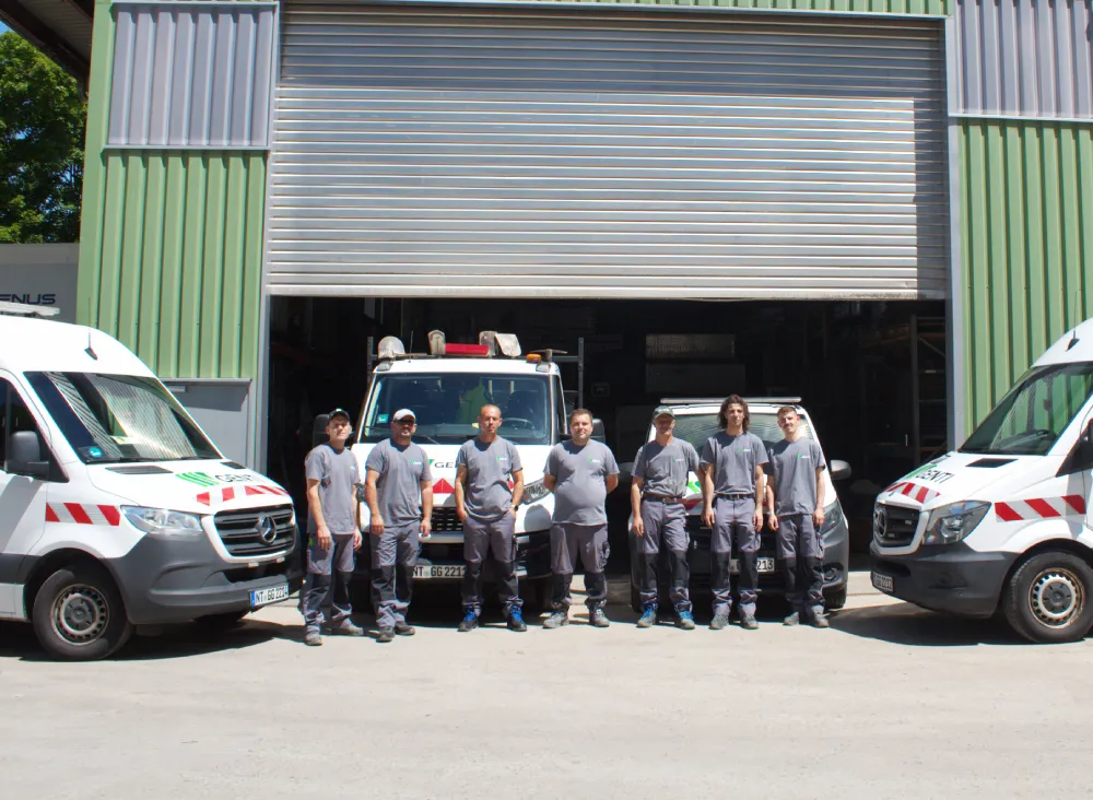 Genti Team vor Firmenfahrzeugen. Service und Wartung.